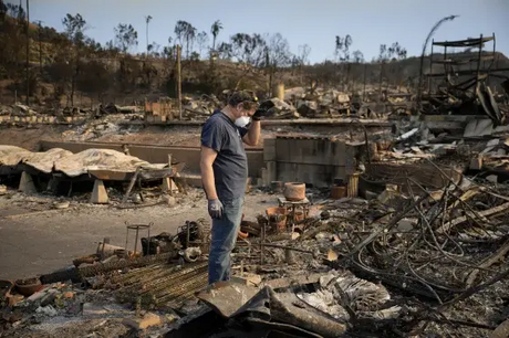 Kevin Marshall sifts through his mother's fire-ravaged property in the Pacific Palisades neighborhood of Los Angeles, on Jan. 11. 